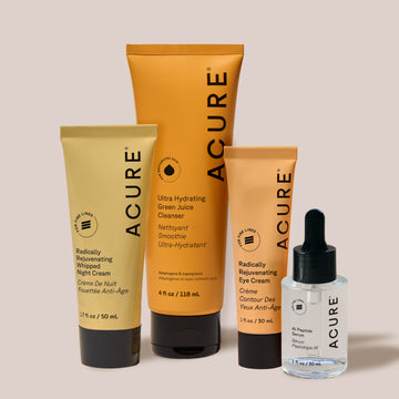 Acure skincare products including a cleanser, night cream, eye cream, and serum on a beige background.